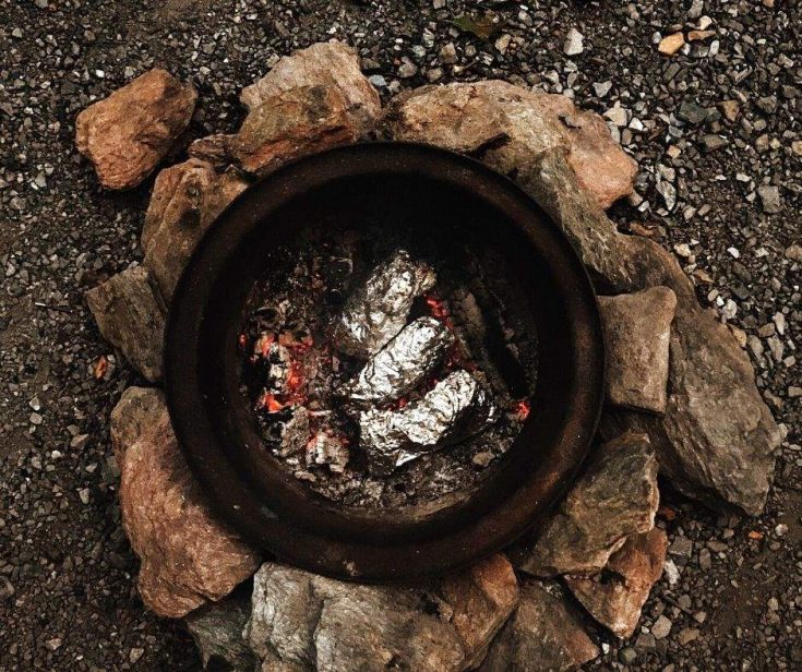 Camping recipes - fish in foil packets cooking over a campfire outside